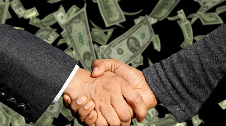 Two businessman handshaking with dollar notes on background