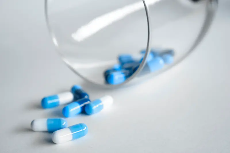 White and blue medication pill in glass
