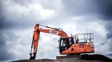 Orange excavator in the middle of wide land area
