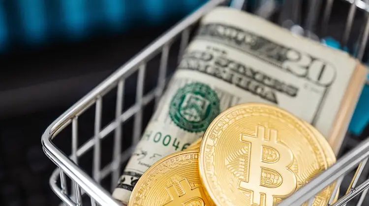 Bitcoin cryptocurrency in mini shopping trolley with dollar bills