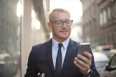 Man wearing eyeglasses reading text on his smartphone