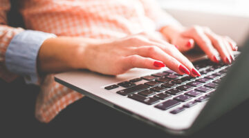 Woman with red nail polished typing on her laptop
