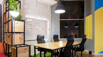 Startup office with desk, and black chairs. Whiteboard beneath HVAC system on the wall.
