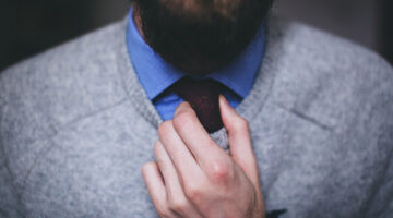 Man wearing gray top fixing the necktie