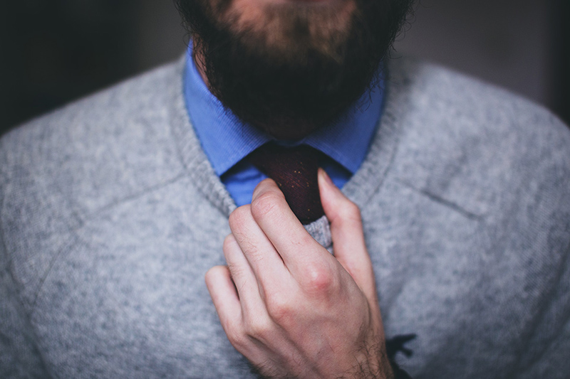 Man wearing gray top fixing the necktie