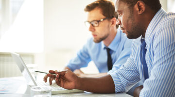 Man pointing at laptop for his colleague