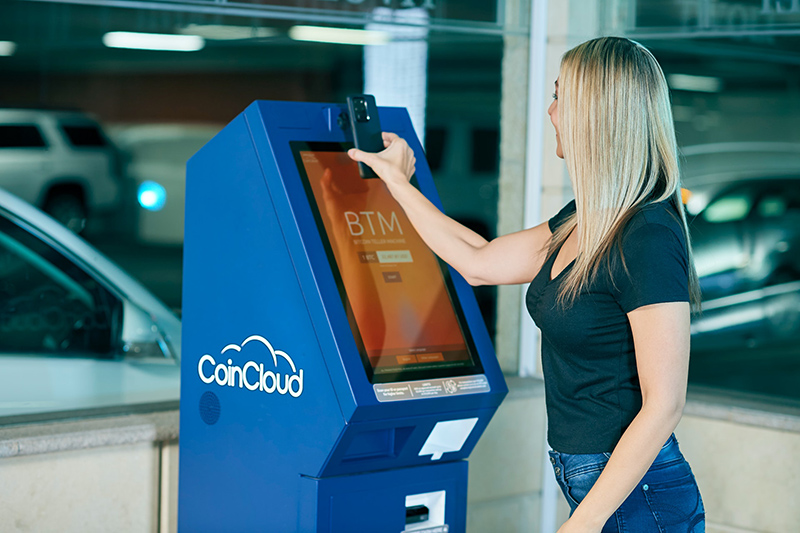 Woman in black tank top standing near blue and black atm machine