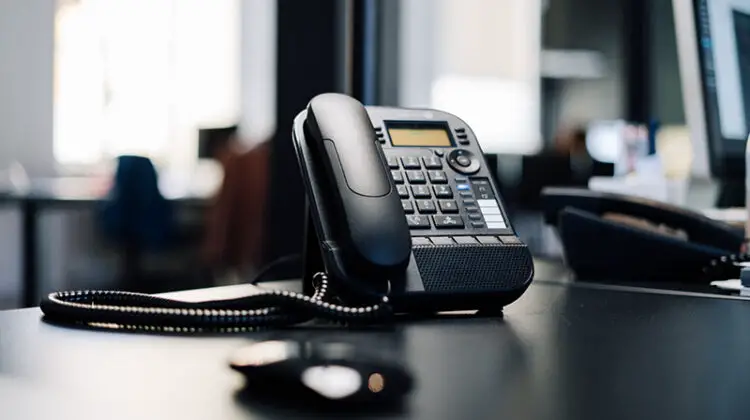 Black IP phone on black desk