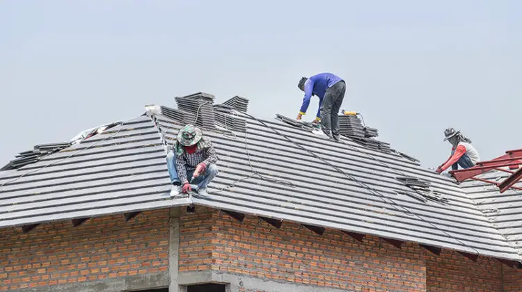 Workers installing concrete tiles on the roof