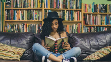 young woman with black hat reading books in the couch