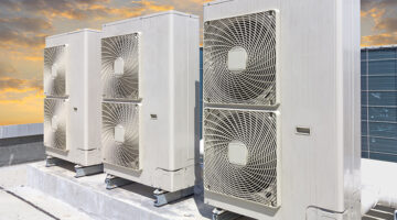Air compressor on roof of factory with blue sky background.