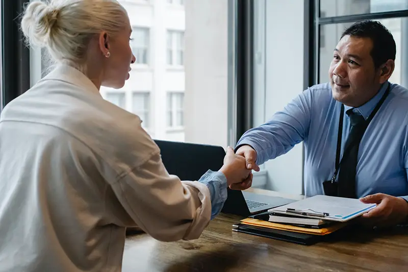 Ethnic businessman shaking hand with woman applicant in the office