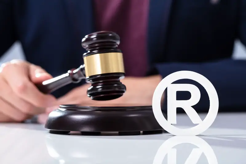 A Person s Hand Hitting The Gavel On Sounding Block Near Trademark Icon Over Desk