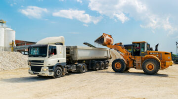 Brown loader beside white cargo truck