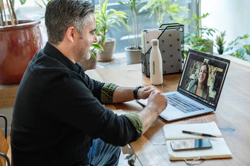 man in black sweater using macbook pro for virtual meeting
