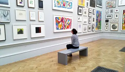 Woman sitting while watching arts on gallery