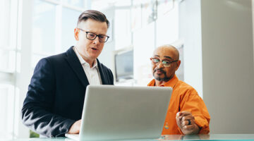 Man using silver laptop beside another man