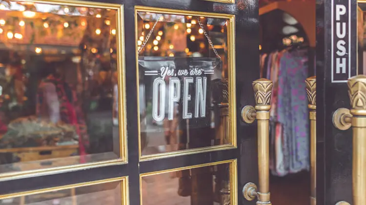 Close up photo of black door with signage yes we're open