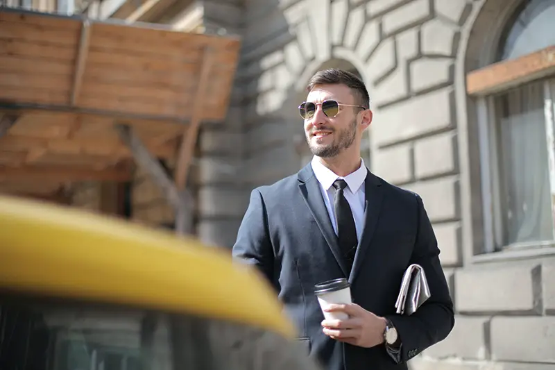 man in black suit holding a cup of coffee
