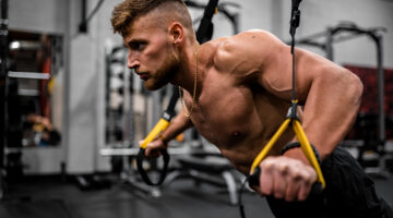 topless man in black pants holding black and yellow exercise equipment