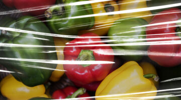 Fresh bell peppers covered with plastic wrap