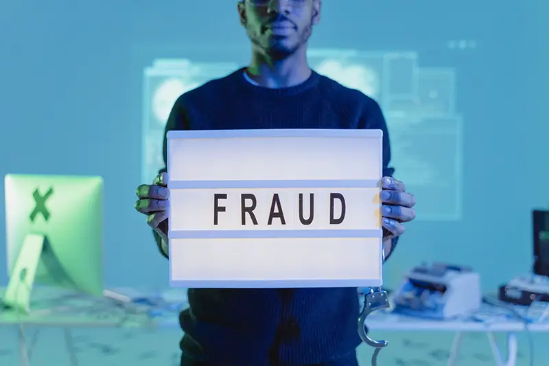 Man in black sweater holding a fraud banner