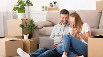 Happy couple sitting on the floor near gray couch