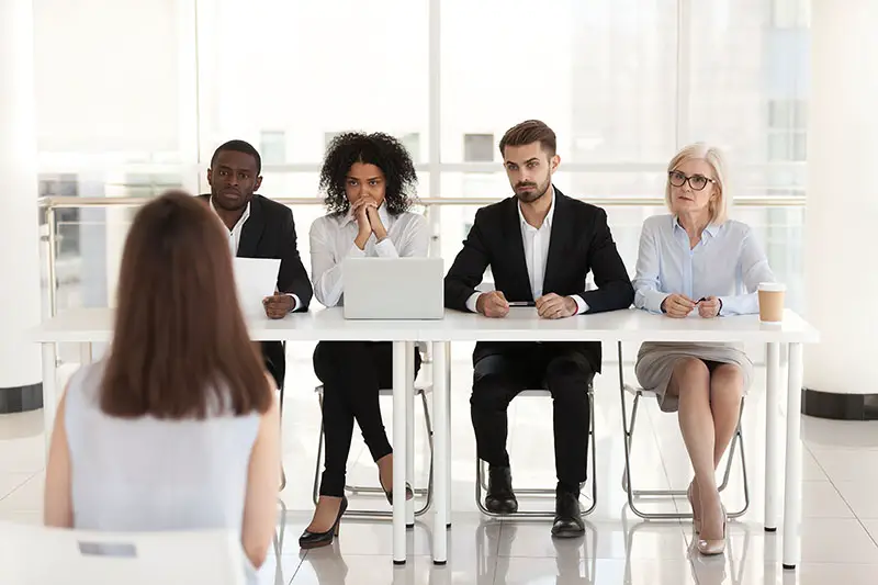 Diverse HR managers listen to female job candidate speaking during work interview in office