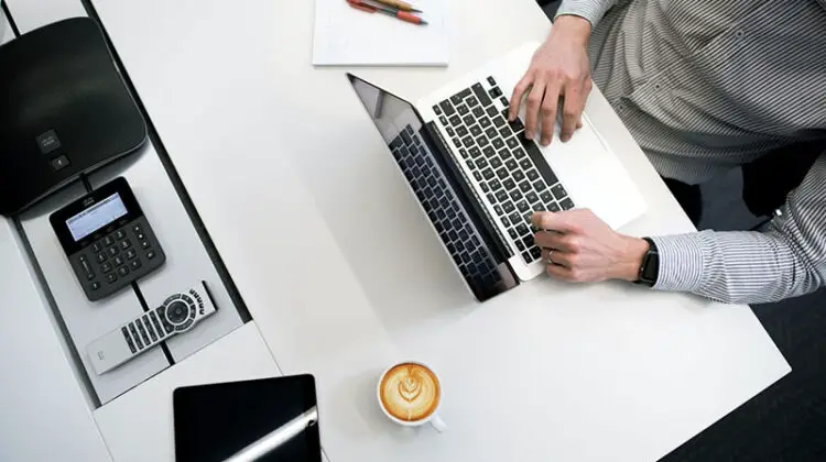 Man in stripe long sleeves working in front of his laptop