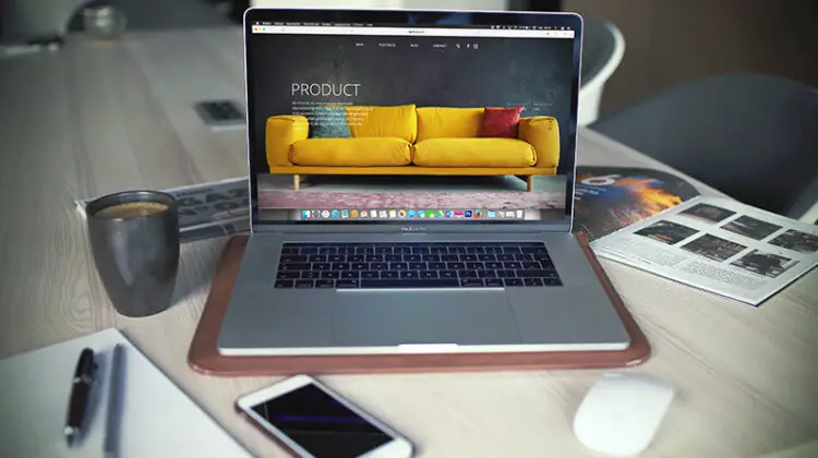 turned on Mac book pro beside gray mug