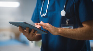 Surgeon Uses Digital Tablet Computer Health Care Vitals Monitoring Computer Machine