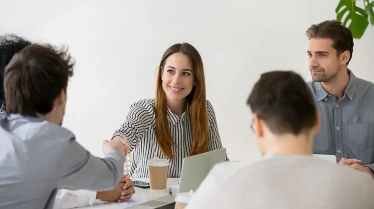 Smiling businesswoman shaking hand of male partner at the office meeting