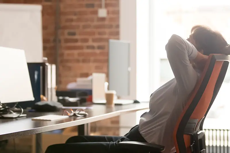 businesswoman office worker holding hands behind head sitting in ergonomic chair