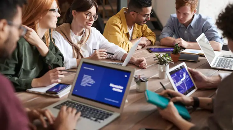 Group of diverse people working on their laptop on the top of brown wooden table