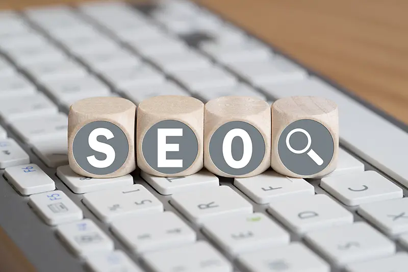cubes with the acronym SEO on top of white keyboard