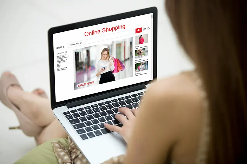 Young shopper woman shopping online on clothing website using laptop