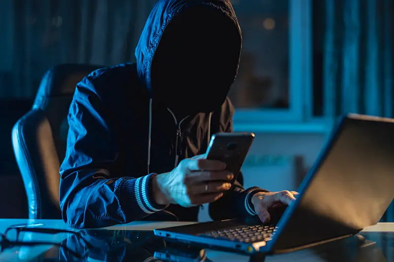 Anonymous hacker programmer uses a laptop to hack the system in the dark