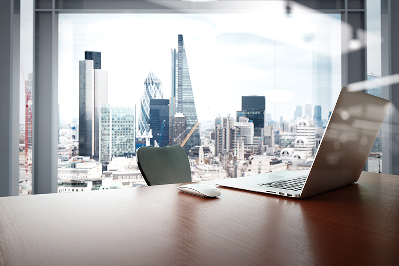 Office workplace with laptop and smart phone on wood table with london city background