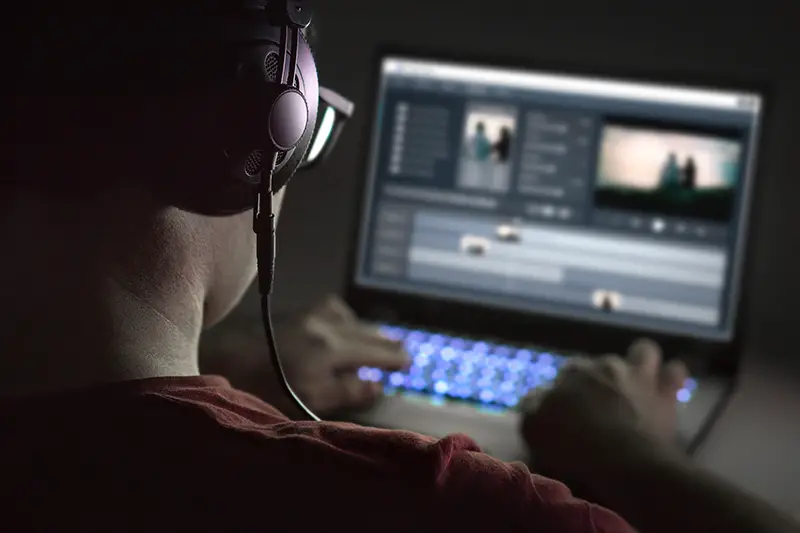 Man wearing headphone editing a video on his laptop