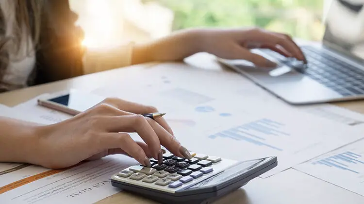 Close up Business woman using calculator and laptop for do math finance on wooden desk in office