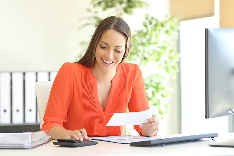 Businesswoman wearing orange blouse doing accounting and invoices