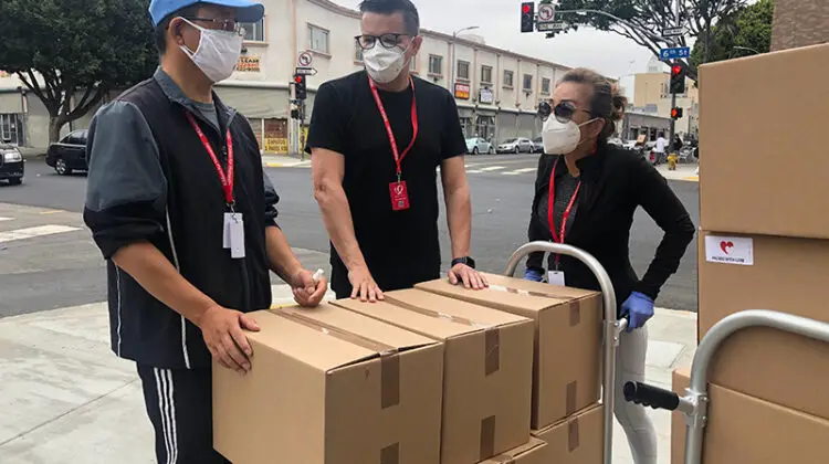3 men in black shirt beside brown cardboard boxes