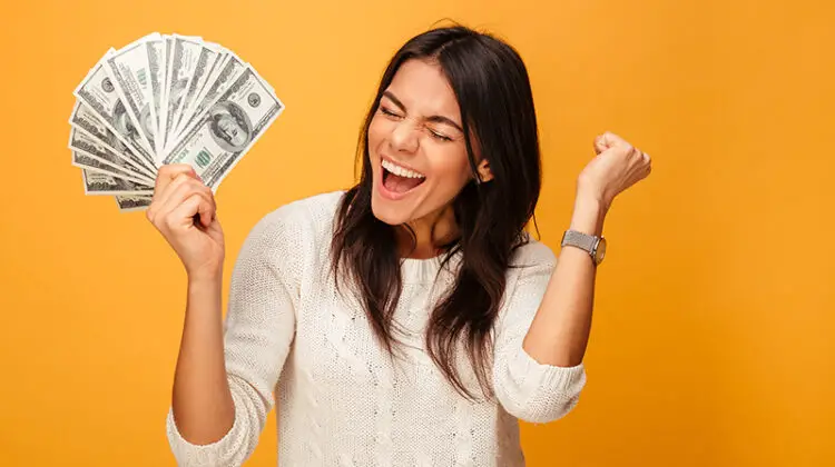 Portrait of a cheerful young woman holding money banknotes