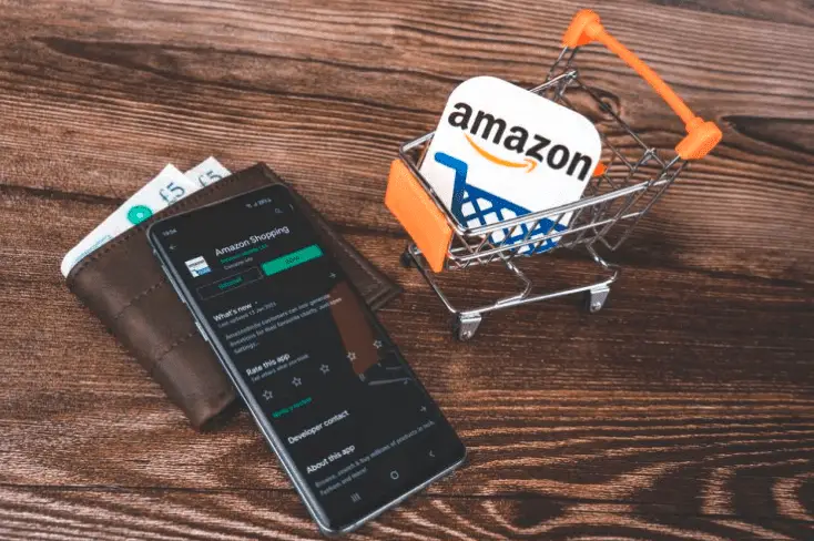 Black smartphone and wallet near amazon logo in shopping cart