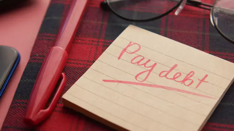 Pay debt text written in brown note pad