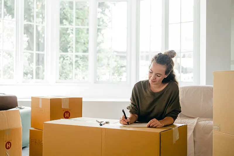 woman signing box near large window