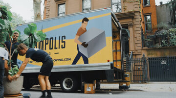 three men moving big plants beside truck