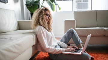 Woman sitting on floor while using laptop
