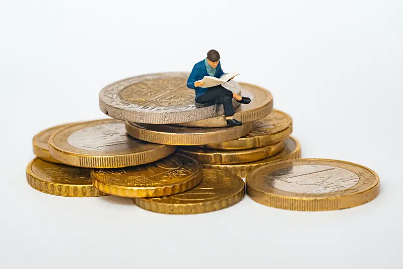 miniature man sitting on the coins
