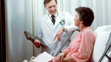 doctor holding a brown record book beside a patient
